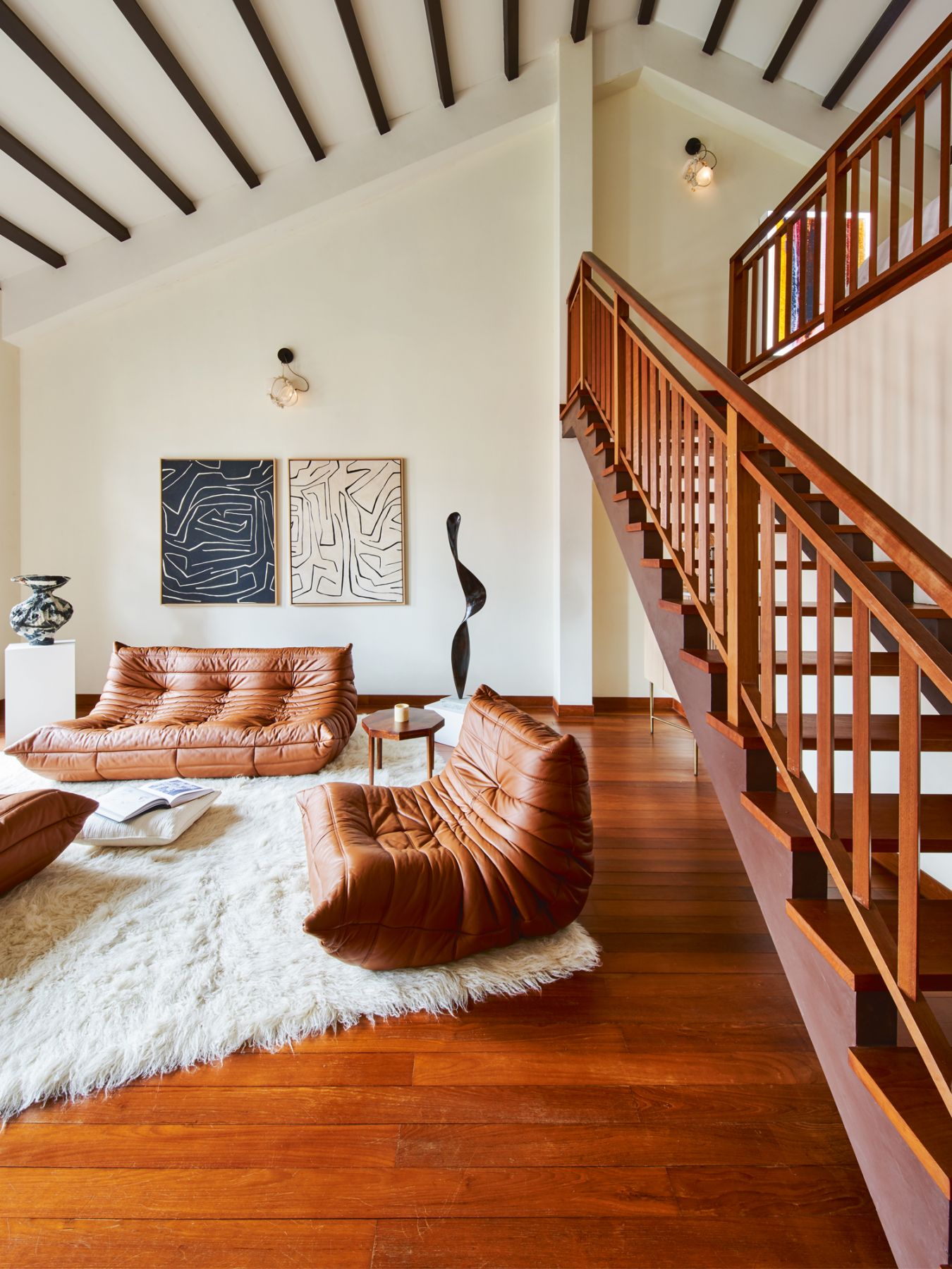 The living area in the attic features the Ligne Roset Togo sofa and settees by Michel Ducaroy from Grafunkt, Lindsey Adelman pendant lights repurposed as wall sconces, fabrics from Kelly Wearstler framed as wall-hung artworks, and a cushion from Pierre Frey