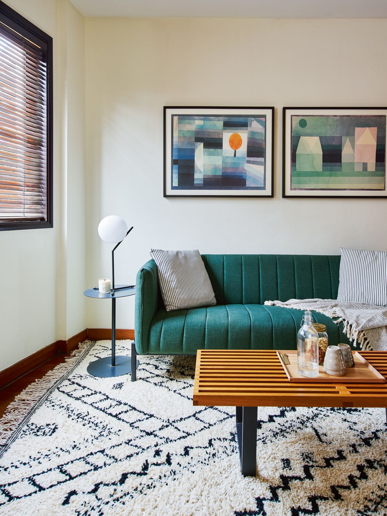 Wall-hung artworks echo the emerald green hue of the sofa in this bedroom
