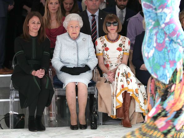 LONDON, ENGLAND - FEBRUARY 20: Queen Elizabeth II sits next to Anna Wintour (R) and Caroline Rush, chief executive of the British Fashion Council (BFC) (L) as they view Richard Quinn's runway show before presenting him with the inaugural Queen Elizabeth II Award for British Design as she visits London Fashion Week's BFC Show Space on February 20, 2018 in London, United Kingdom. (Photo by Yui Mok - Pool/Getty Images)