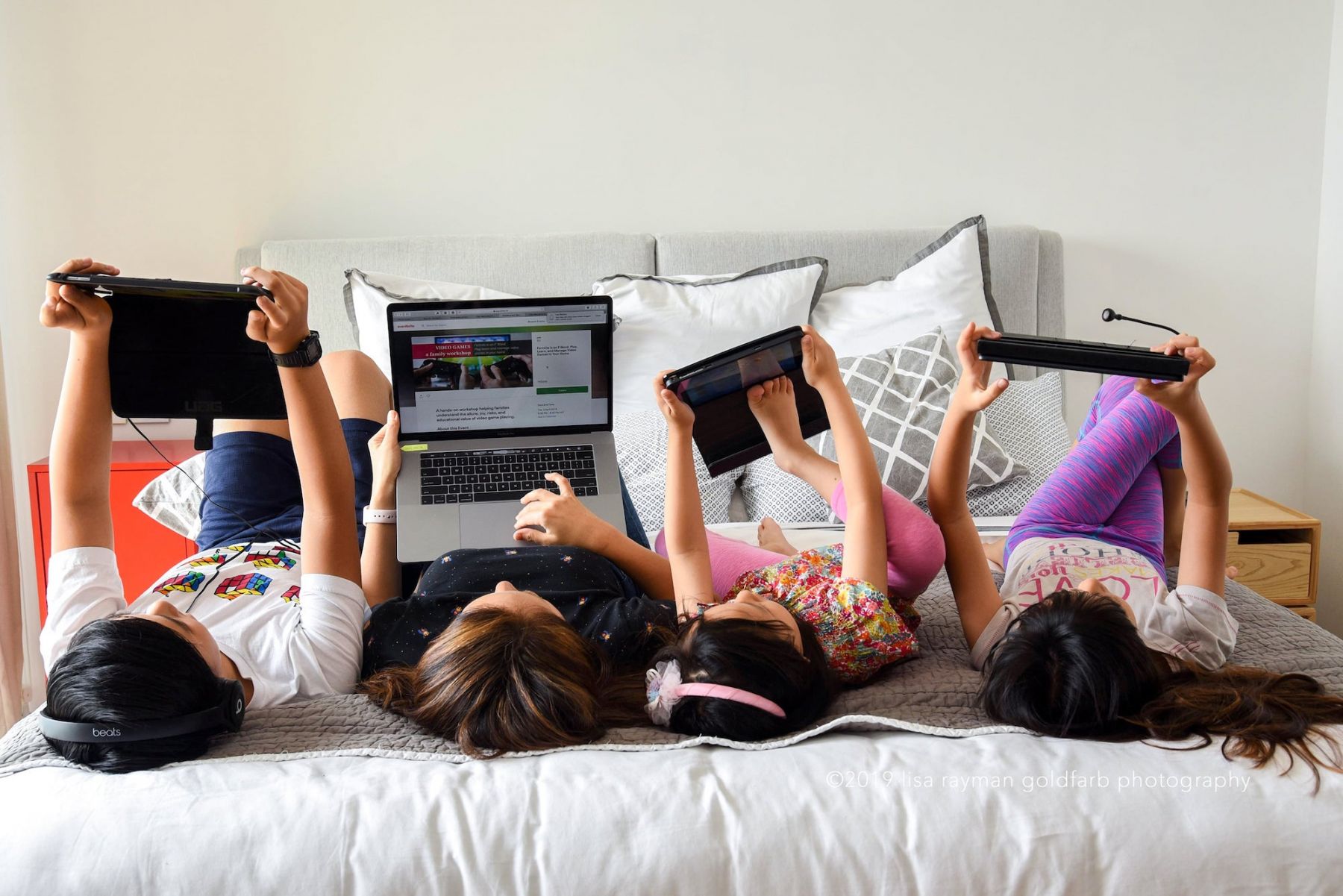 Arcadia Kim of Infinite Screentime and three kids lying in bed looking at their screens