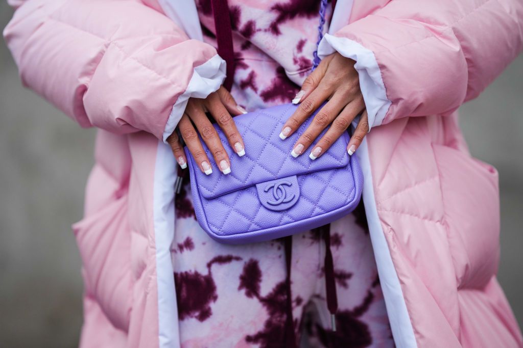 PARIS, FRANCE - NOVEMBER 30: Patricia Gloria Contreras wears a pink / purple / white tie and dye hoodie sweaters, matching pink / purple / white tie and dye sport pants / jogger pants, a purple shiny grained leather crossbody bag from Chanel, a pale pink with white interior oversized puffer jacket, during a street style fashion photo session, on November 30, 2021 in Paris, France. (Photo by Edward Berthelot/Getty Images)