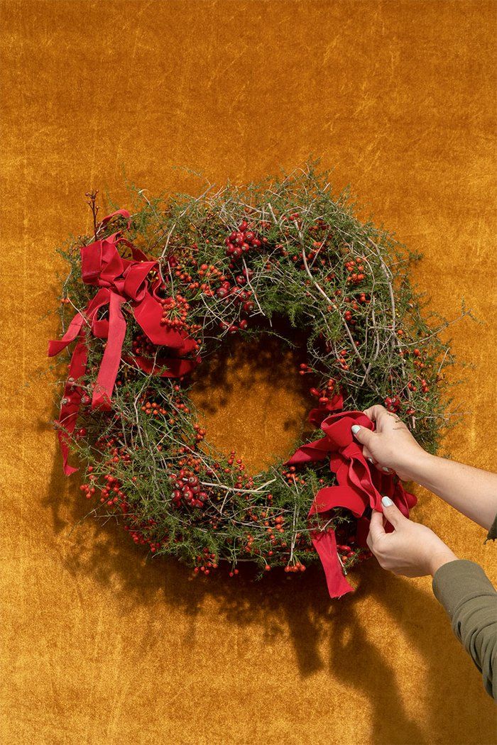 Handmade with rose hips and asparagus vine, the wreath brings seasonal joy