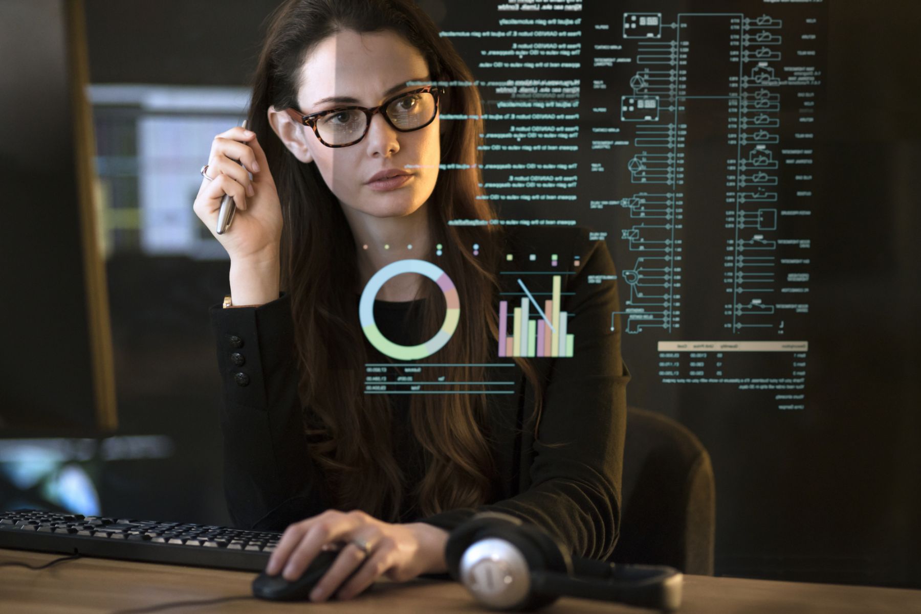 Stock photograph of a professional, good looking woman studying a see-through display showing a variety of data & information.