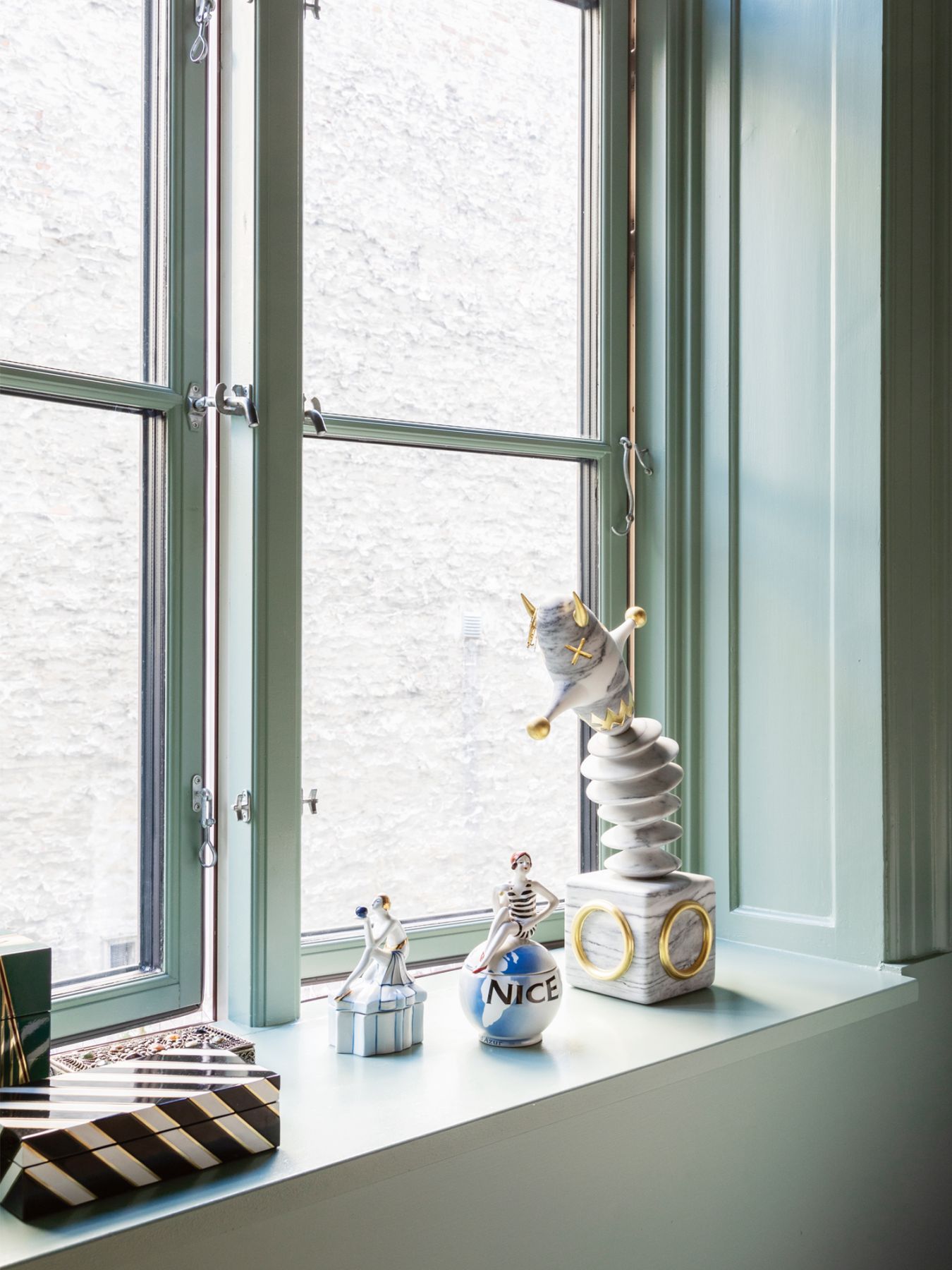 The windowsill features an array of ceramic objects, including a jack-in-the-box sourced from a flea market in Nice, France