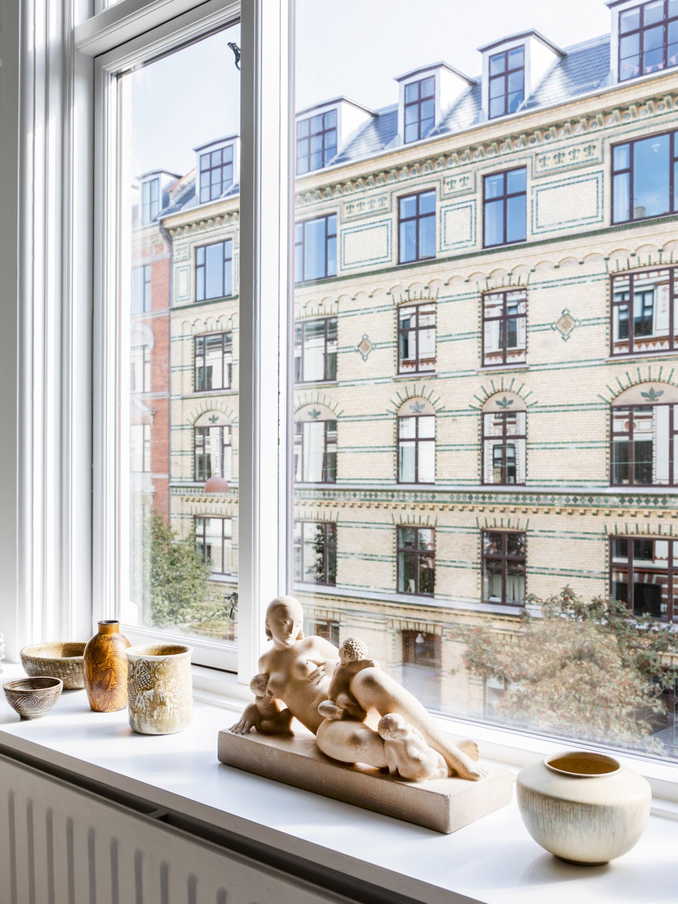An assortment of ceramic vessels and a sculpture create visual interest on a windowsill