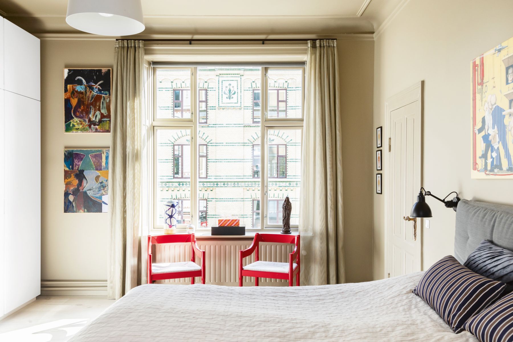 These red Fritz Hansen Carimate chairs by Vico Magistretti add pops of colour to the master bedroom