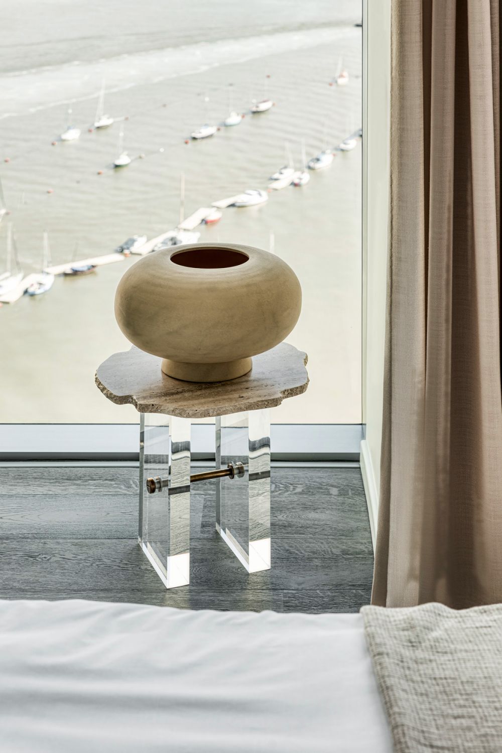Inspired by nature, this Yin side table features a natural travertine top with textured edges juxtaposed against the perspex and brass legs