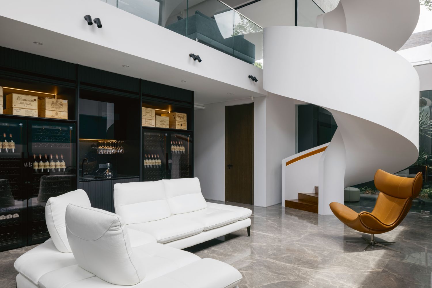 Located next to Nicoletti sofas, these full-height dark wood shelves showcase the owners’ collection of spirits in a stylish, temperature-controlled environment