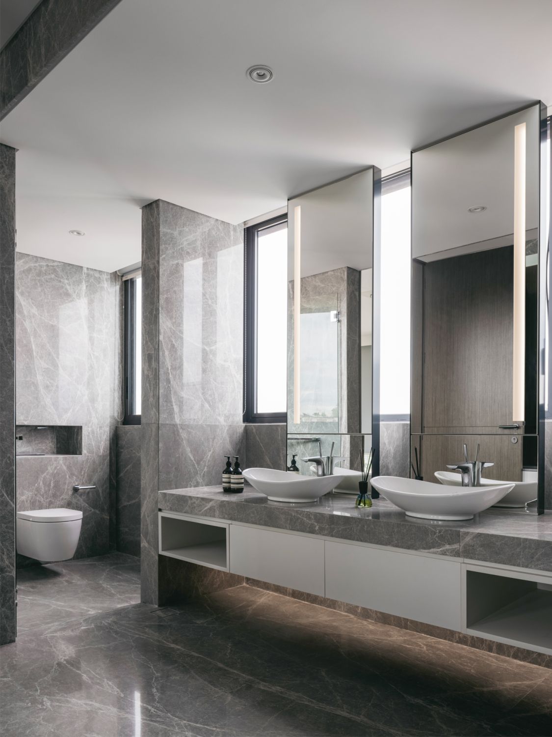The master bathroom features his-and-hers vanities, dark grey marble tiles and bathroom fittings from Hansgrohe and Duravit