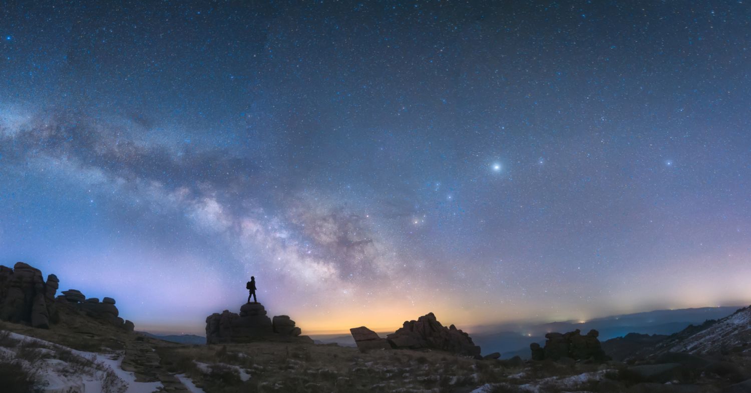 A man standing next to the Milky Way galaxy