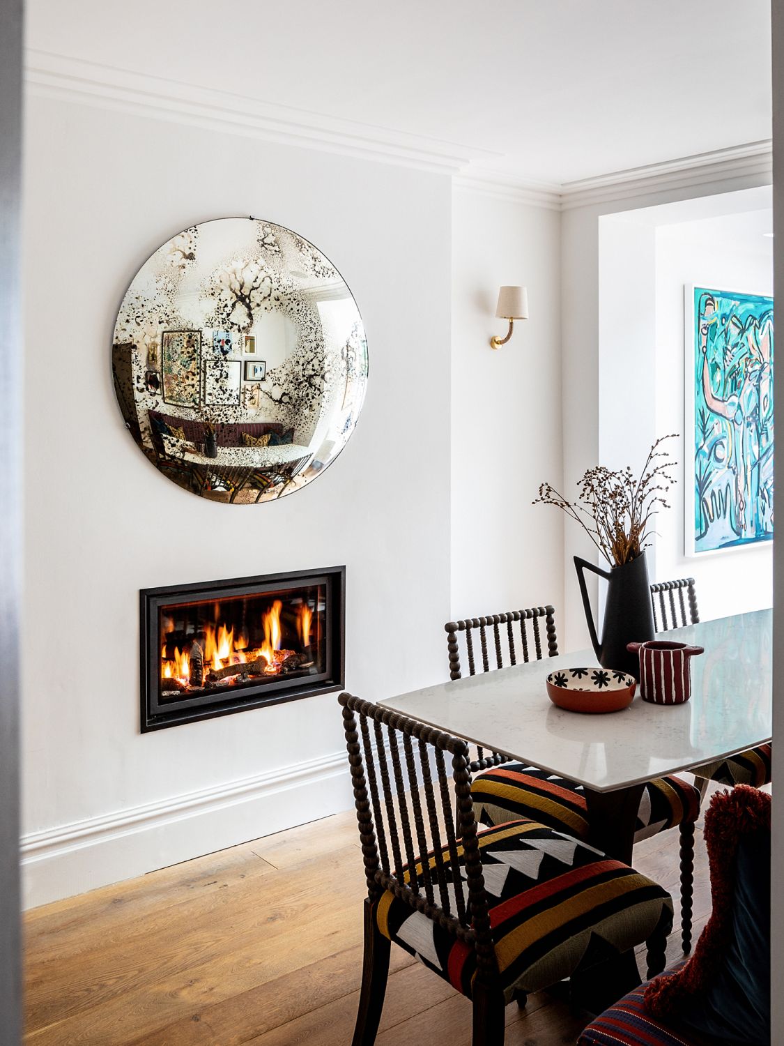 A wall-mounted distressed glass mirror adds a charming appeal atop the fireplace