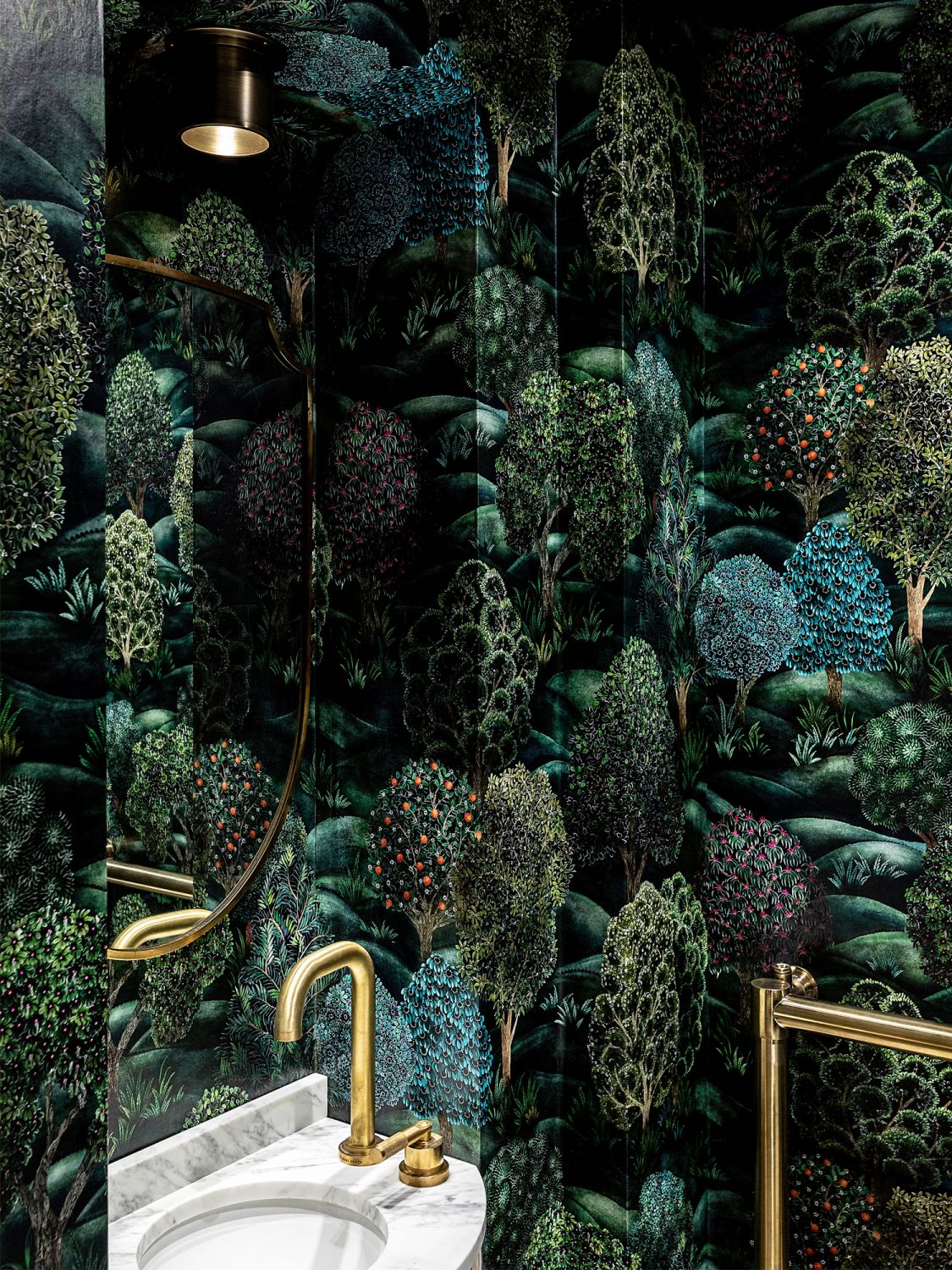 The guest bathroom is lined with a lush wallpaper that transforms the tiny space into an enchanted forest