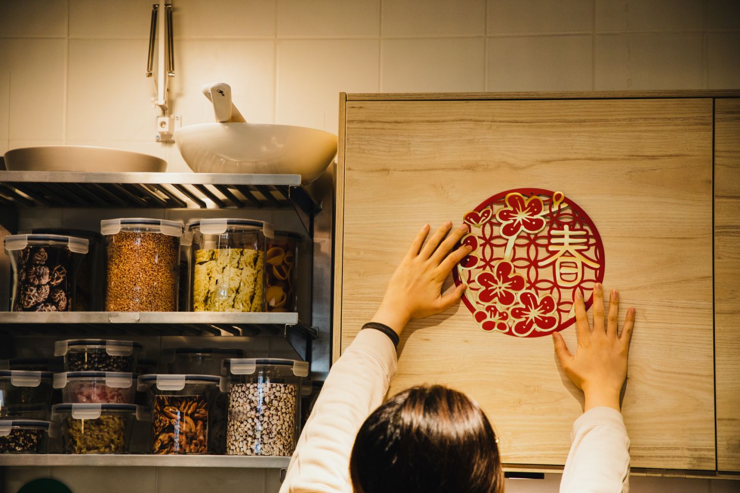 Asian female celebrating Chinese new year by putting up paper craft to the wall cabinet