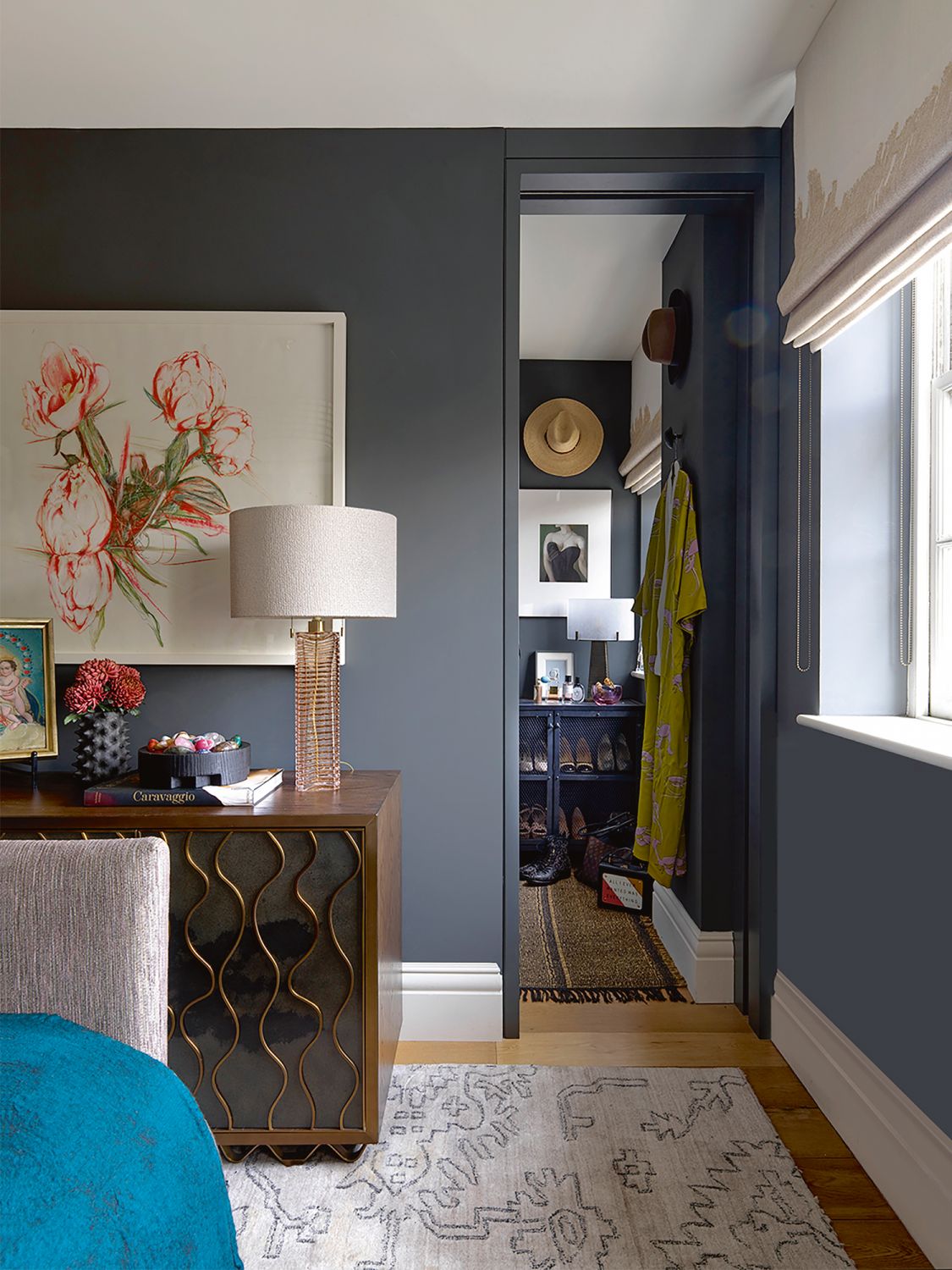 The dark and moody palette of the master bedroom stands in contrast to the rosy hues in the rest of the apartment