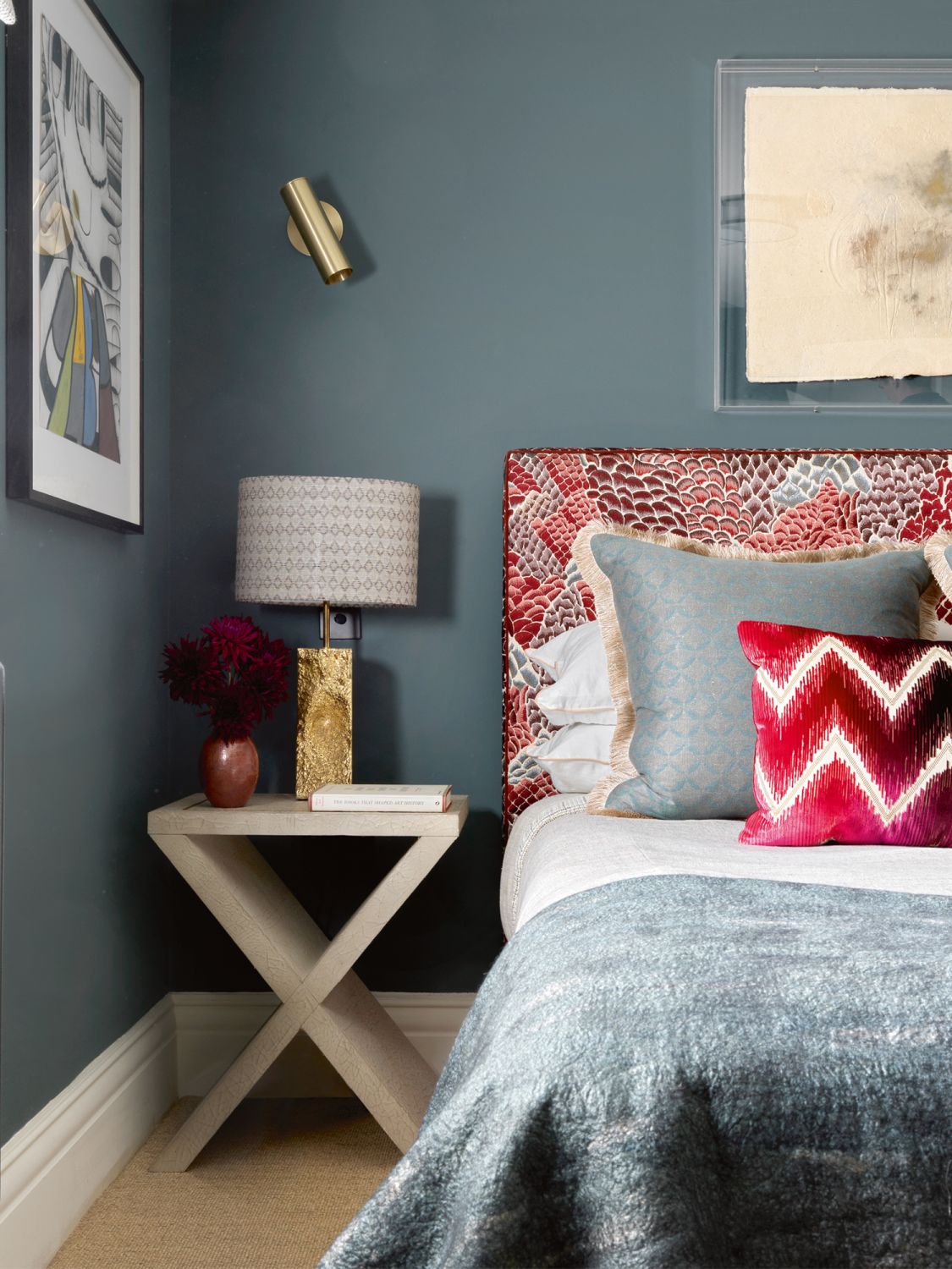A headboard upholstered in the Le Rocher fabric from Pierre Frey’s Broderie collection is paired with zigzag cushions in a Schumacher fabric and a Claudy Jongstra throw from Willer Gallery, and offset by walls clad in Inchyra Blue paint from Farrow & Ball