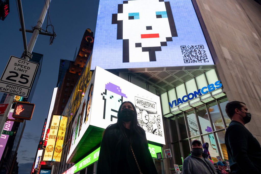NEW YORK, NEW YORK - MAY 12: People walk past CryptoPunk digital art non-fungible token (NFT) displayed on a digital billboard in Times Square on May 12, 2021 in New York City. The image is part of SaveArtSpace's
