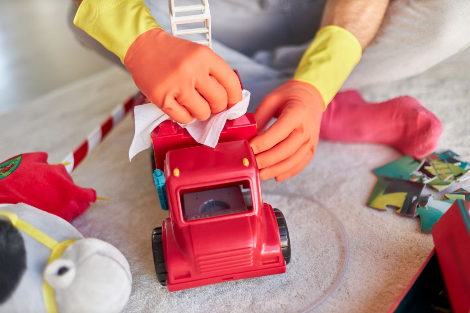 Various photos of a man disinfecting and cleaning children's toys with disinfectant wipes while wearing rubber gloves in yellow and orange
