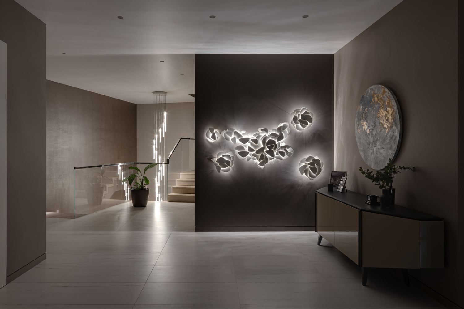 An intricate Art et Floritude lighting piece is displayed in the hallway, paired with a chest of drawers from Cattelan Italia and a round painting by Ukraine artist Mariia Vozvyshaieva