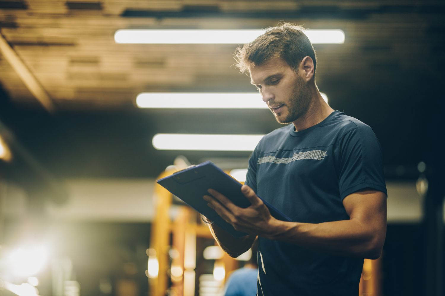 Young coach making a training plan in a gym.