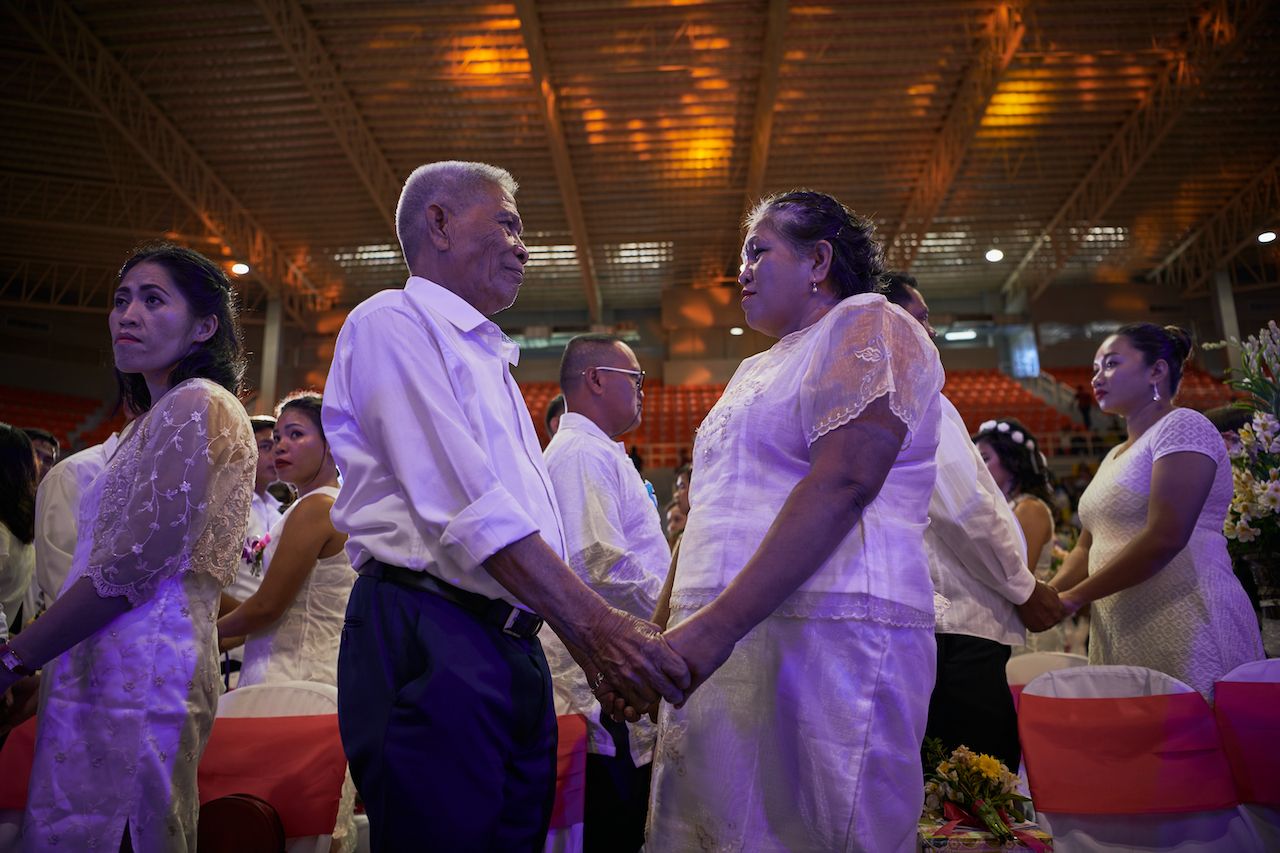 STA ROSA PHILIPPINES - FEBRUARY 14: Newly-wed couples hold hands as they attend a mass wedding as they mark Valentines day amidst fears of the China COVID 19 virus on February 14, 2020 in Sta Rosa, Laguna, South of Manila, Philippines. Fear of getting infected with the China COVID-19 virus continues in the Philippines as the first reported death due to infection was reported last week in the country. (Photo by Jes Aznar/Getty Images)