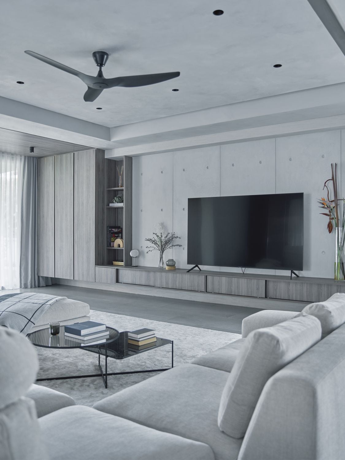 The concrete feature wall adds a modern touch to the living room’s calming, neutral palette