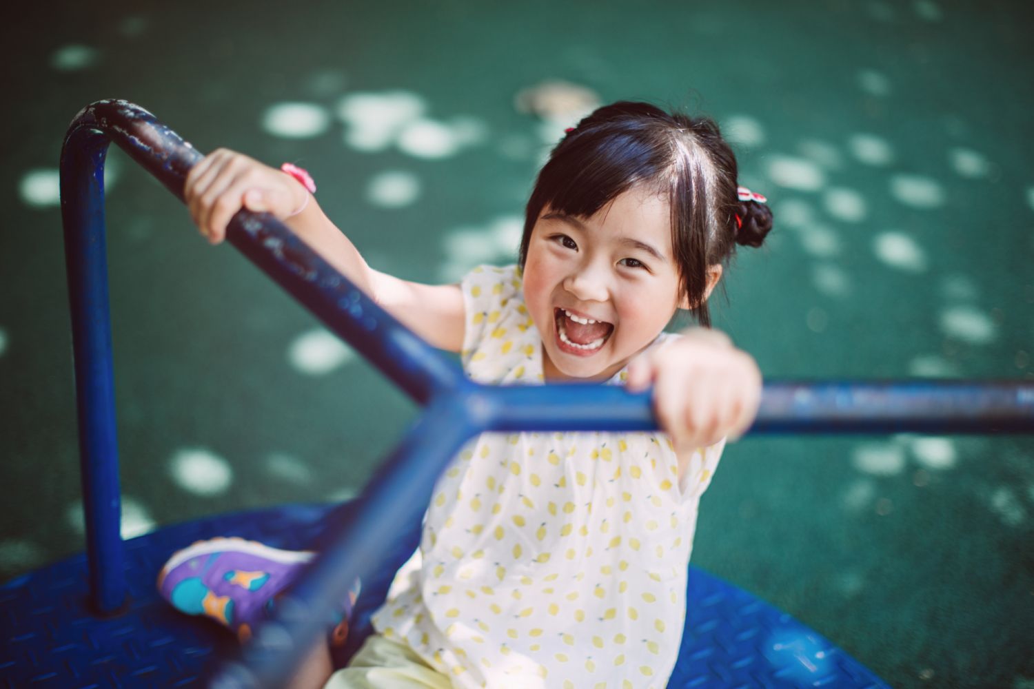 Lovely little girl playing on the merry go round in the playground joyfully