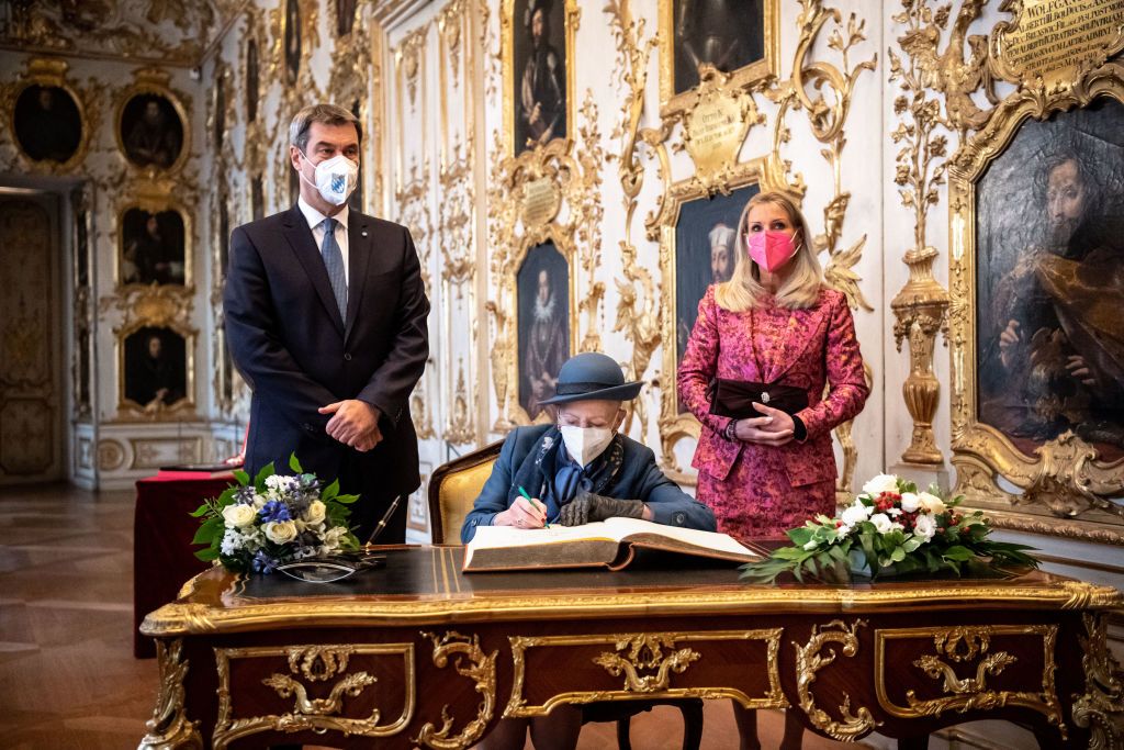 MUNICH, GERMANY - NOVEMBER 12: Queen Margrethe II of Denmark (M) signs in the Bavarian State Government's guest book next to Markus Söder (CSU), party chairman and Prime Minister of Bavaria and wife Karin Baumüller-Söder in the Munich Residence on November 12, 2021 in Munich, Germany. The queen and the heir to the throne are on a state visit to Germany lasting several days. (Photo by Matthias Balk - Pool/Getty Images)