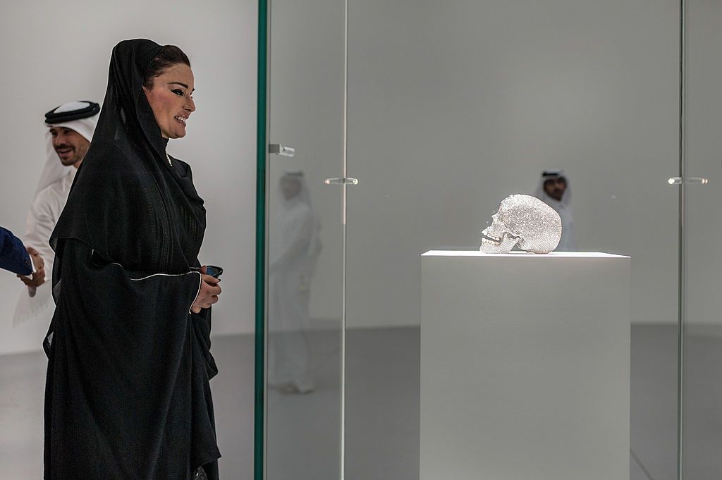 DOHA, QATAR - OCTOBER 09: Qatar's First Lady Sheikha Mozah bint Nasser al-Missned observing 'For the love of God' a skull made of diamonds at the Relics Exhibition by Damien Hirst at Al Riwaq space next to Doha's Museum of Islamic Art on October 9, 2013 in Doha, Qatar. (Photo by Niccolo Guasti/Getty Images)