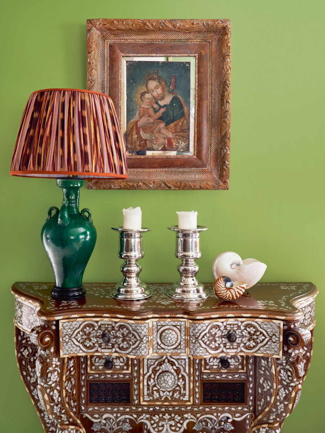 The bone-inlay table is a family heirloom, matched with a green lamp and silver candelabras from Mexico