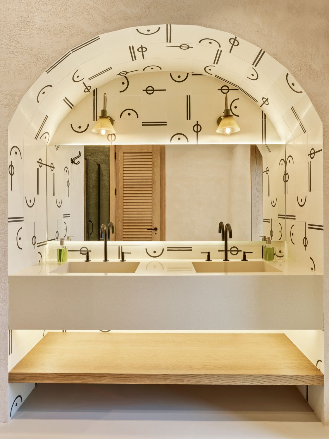 A wallpaper with abstract motifs clads the wall tiles at the vanity, bringing a playful touch to this bathroom