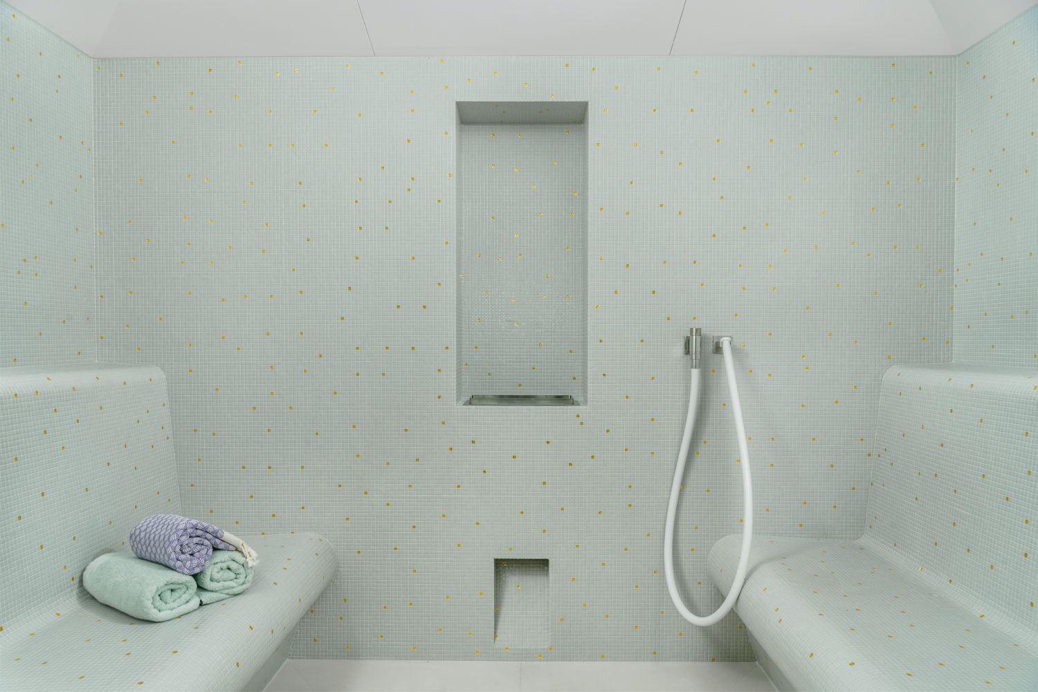 The steam room features glass mosaic wall tiles by Bisazza and Vaia bathroom fittings from Dornbracht