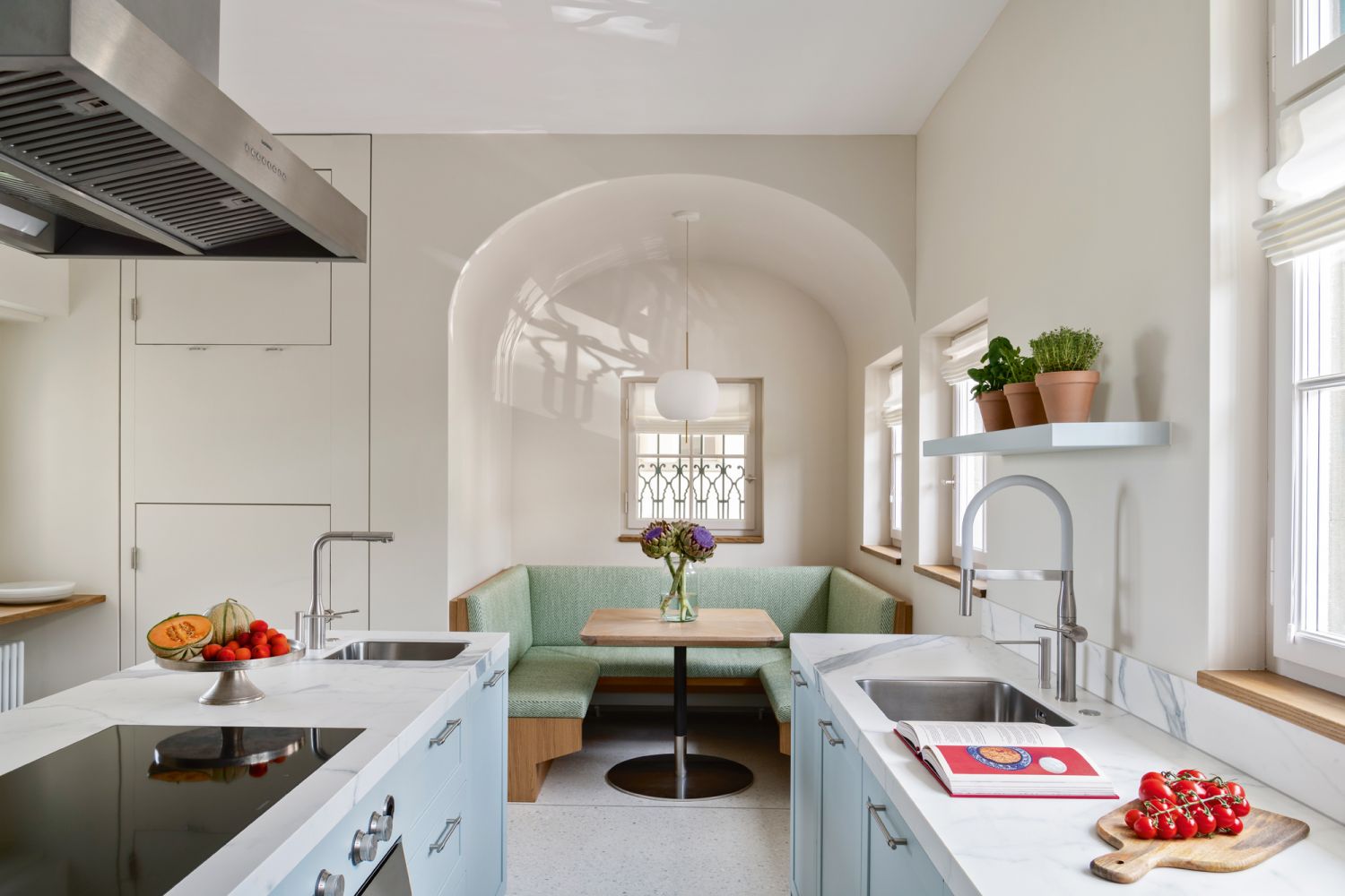 A minimalist Kundalini pendant lamp adds a modern touch to the kitchen, which features pale blue cabinetry with Sapienstone Calacatta Statuario marble counter tops