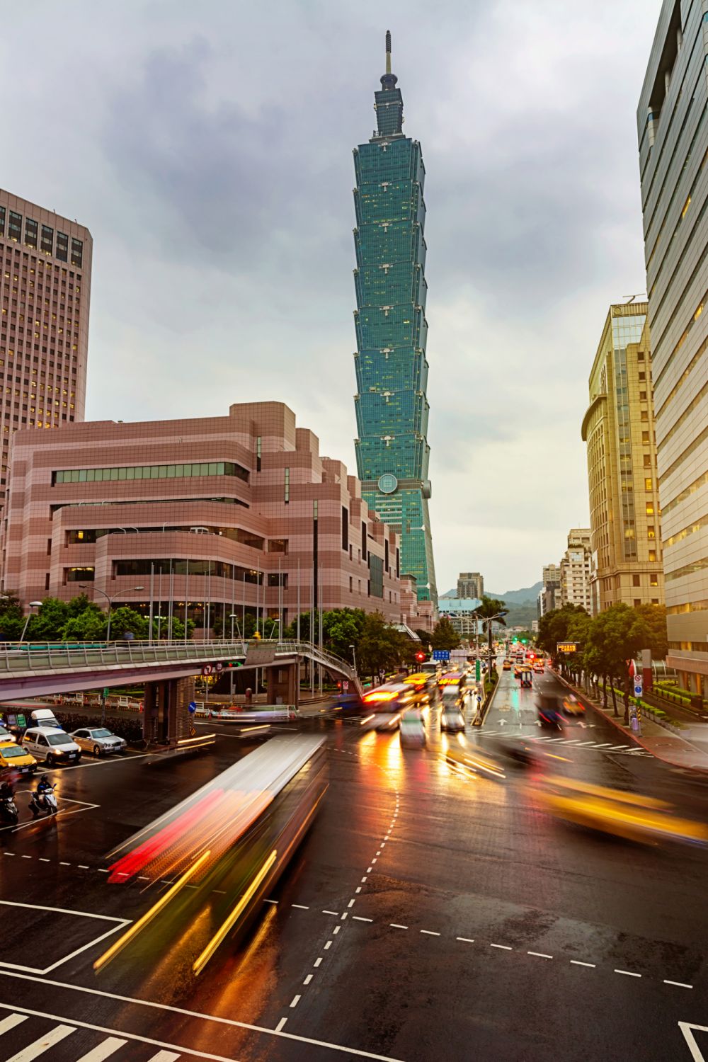 Street scene in the capital city of Taiwan at dusk with motion blurred taxis and traffic in the streets of Taipei. 101 Skyscraper in the background. Long exposure, Taipei, Taiwan. Made with Nikon D810 36MPixel.