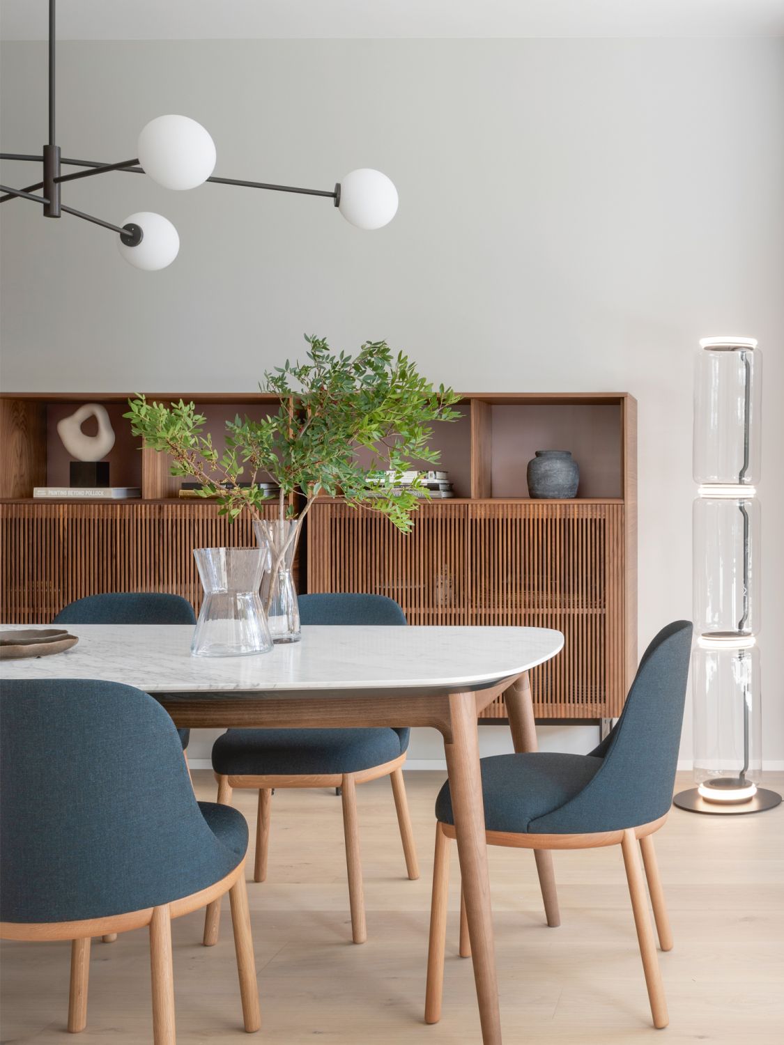 Teal blue Viccarbe Aleta dining chairs by Jamie Hayon and the Flos Noctambule floor lamp by Konstantin Grcic contribute to the cosy feel of the dining area