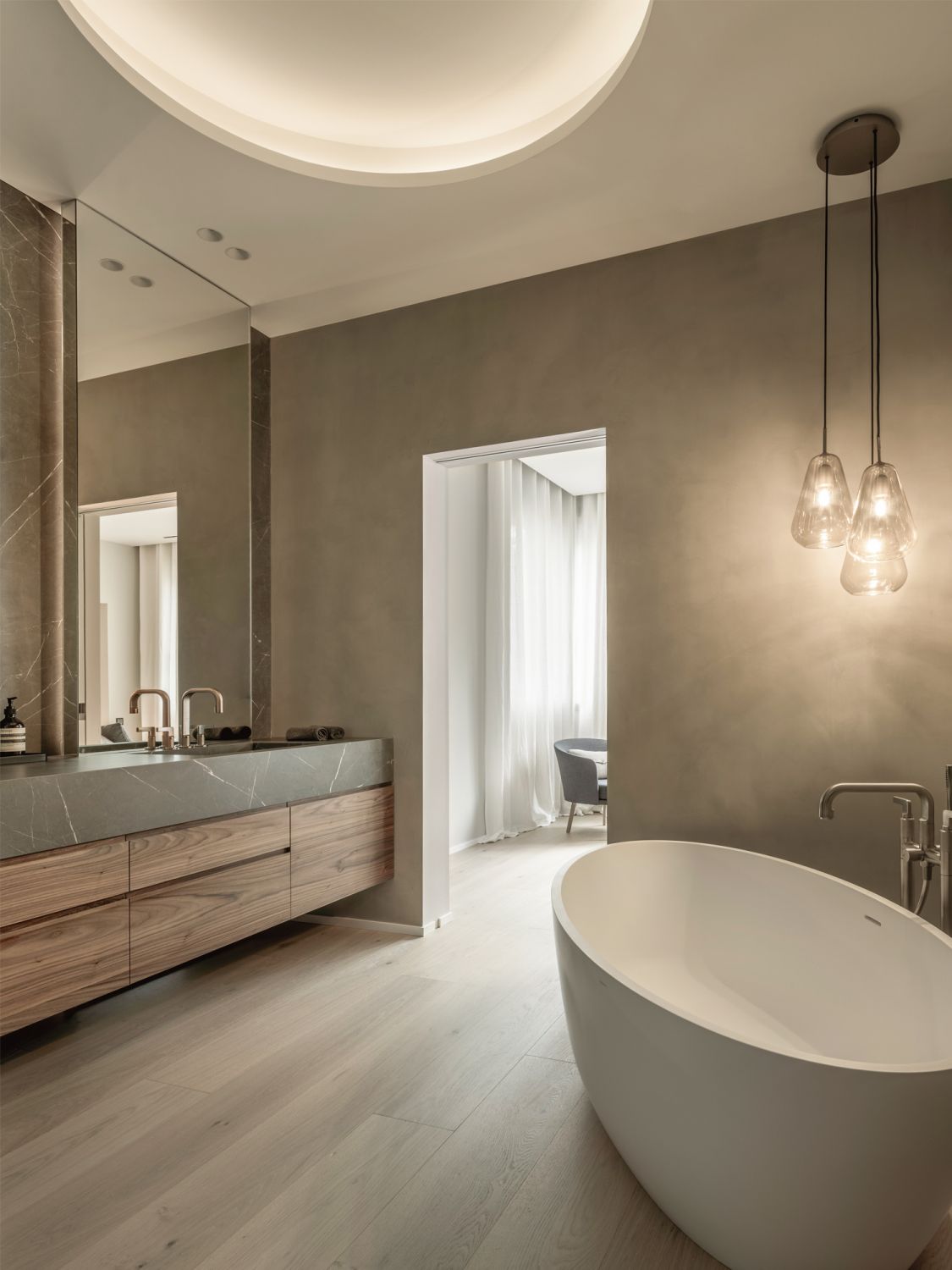 The oval bathtub echoes the curvature of the cove ceiling in the bathroom