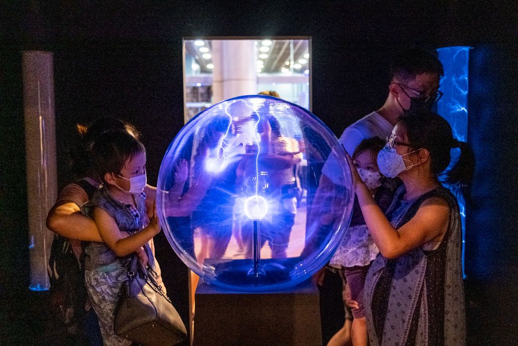 Visitors interact with an exhibition item about electricity in the Hong Kong Science Museum, in Hong Kong, China on May 22, 2021. (Photo by Vernon Yuen/NurPhoto via Getty Images)