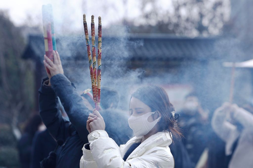 SHANGHAI, CHINA - FEBRUARY 05: People burn incense sticks at the God of Wealth temple on the fifth day of the Chinese New Year on February 5, 2022 in Shanghai, China. (Photo by Yin Liqin/China News Service via Getty Images)