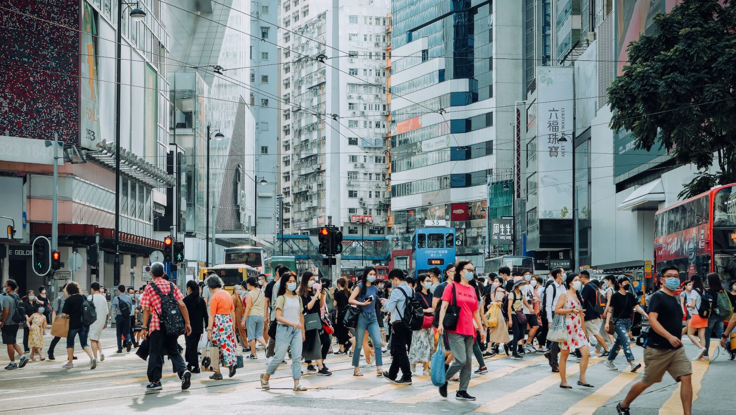 A typical city life in Hong Kong. Crowd of busy commuters crossing the street in downtown district during rush hour against contemporary corporate skyscrapers and city traffic