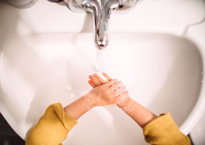 First person perspective of a little girl washing her hands with hand soap & water in the sink.