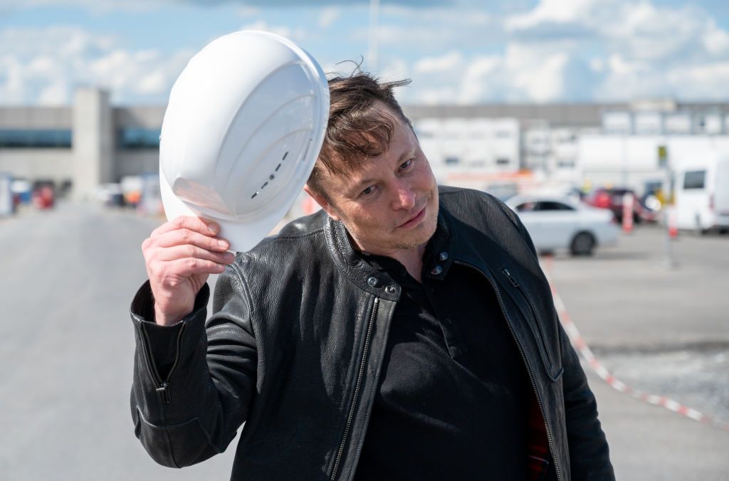 17 May 2021, Brandenburg, Grünheide: Elon Musk, Tesla CEO, stands on the construction site of the Tesla factory and greets with his hard hat. He has taken a look at the construction progress of the new factory in Grünheide near Berlin, which will probably start production several months later than originally planned. The 49-year-old did not initially comment on Monday. Photo: Christophe Gateau/dpa (Photo by Christophe Gateau/picture alliance via Getty Images)