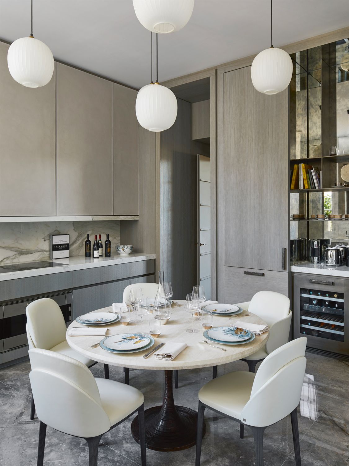 The dining room features a travertine-and-bronze table from Chahan Minassian, Fior di Bosco marble flooring, custom kitchen cabinetry from Obumex and countertops clad in Calacatta Oro Borghini marble