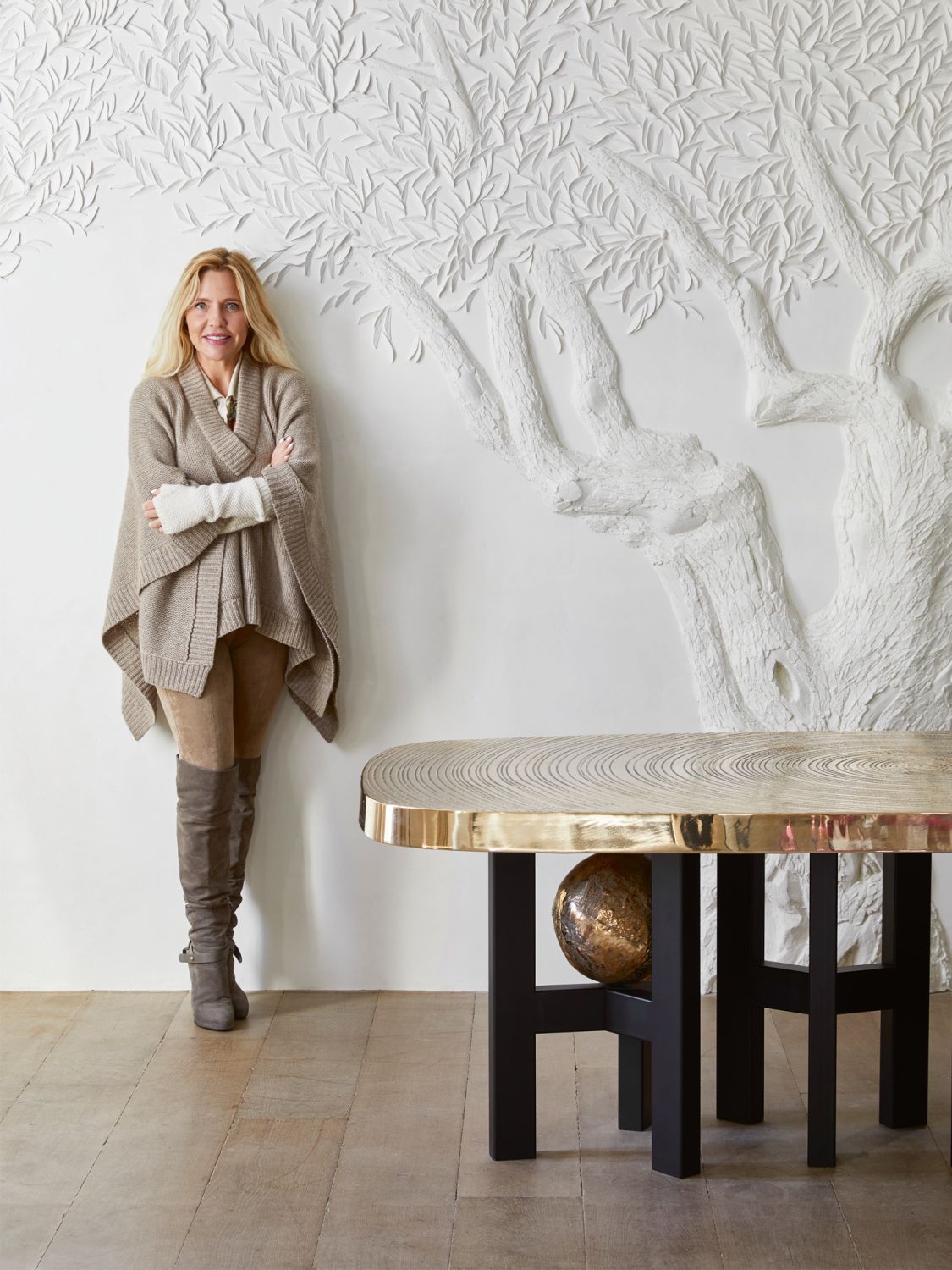 Interior designer Stéphanie Coutas stands next to the botanical mural and a table by Ado Chale in the living room