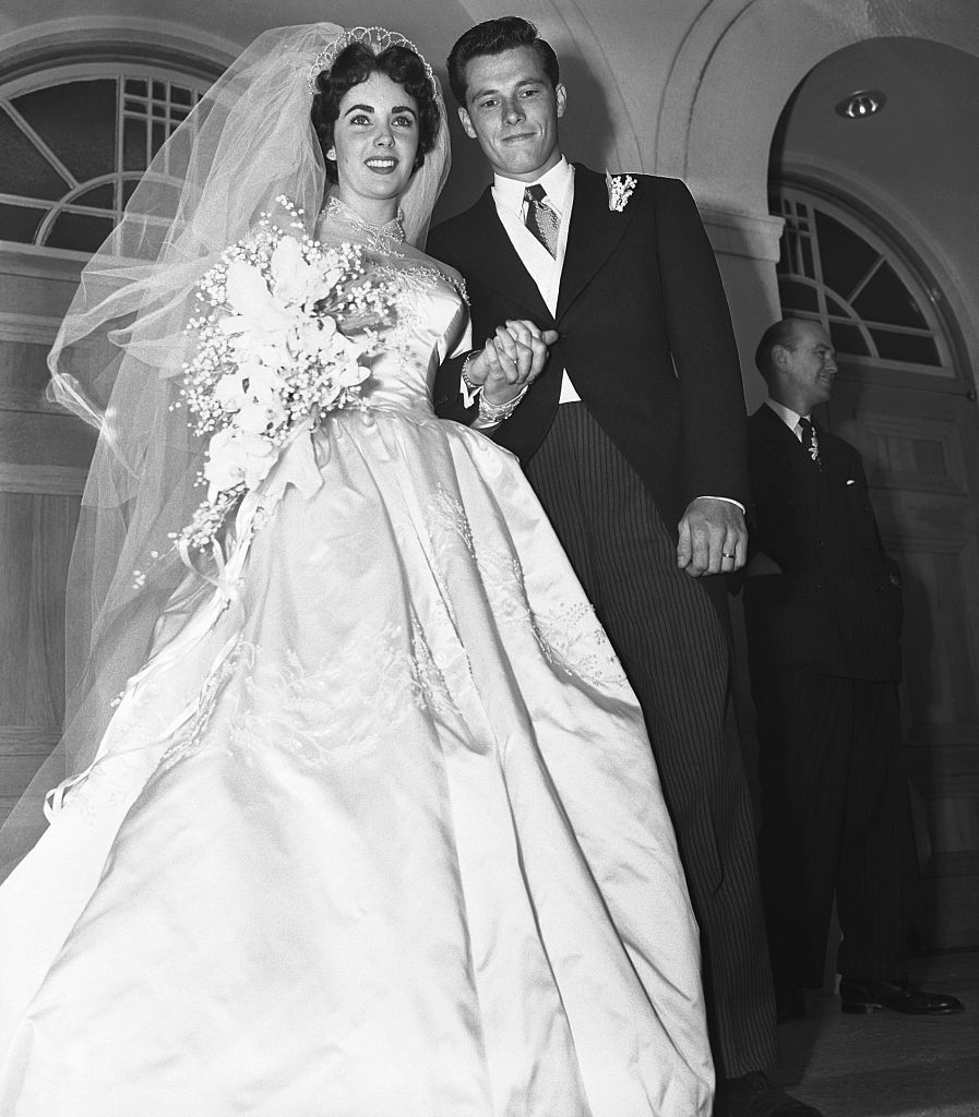(Original Caption) 5/6/1950-Beverly Hills, CA- Mr. and Mrs. Conrad Hilton Jr., pause on the steps of the Church of the Good Shepherd here after their wedding. The bride is the former Elizabeth Taylor, popular Hollywood actress, and the groom is the son of the well-known Hilton Hotel family.