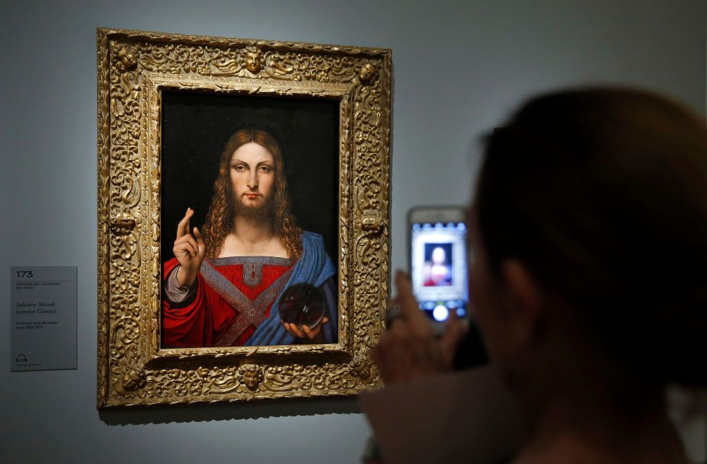 PARIS, FRANCE - OCTOBER 22: A visitor takes a picture of a painting entitled  'Salvator Mundi' by School of Leonardo da Vinci during a press visit of the exhibition "Leonardo da Vinci" at the Louvre museum on October 22, 2019 in Paris. France. This exceptional exhibition will commemorate the 500th anniversary of the death of the famous Italian artist and will be held from October 24, 2019 to February 24, 2020. (Photo by Chesnot/Getty Images)