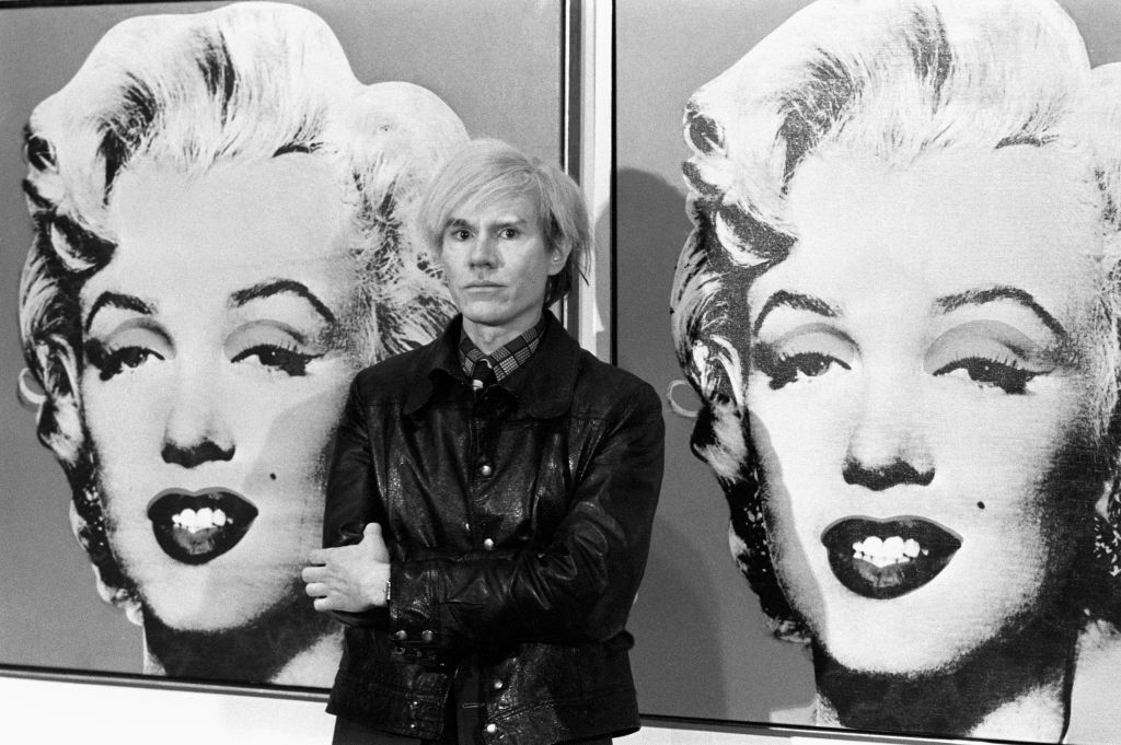 22/02/1987: Died on this day American Pop artist and film maker Andy Warhol America's pop-art painter and film-maker, Andy Warhol, stands in front of his double portrait of the late Hollywood film star, Marilyn Monroe, at the Tate Gallery, Millbank, at a press preview of his exhibition. (Photo by PA Images via Getty Images)