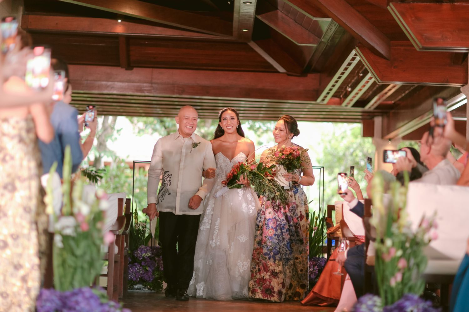 The bride walking down the aisle with her parents, Arlene and Ernest Cu