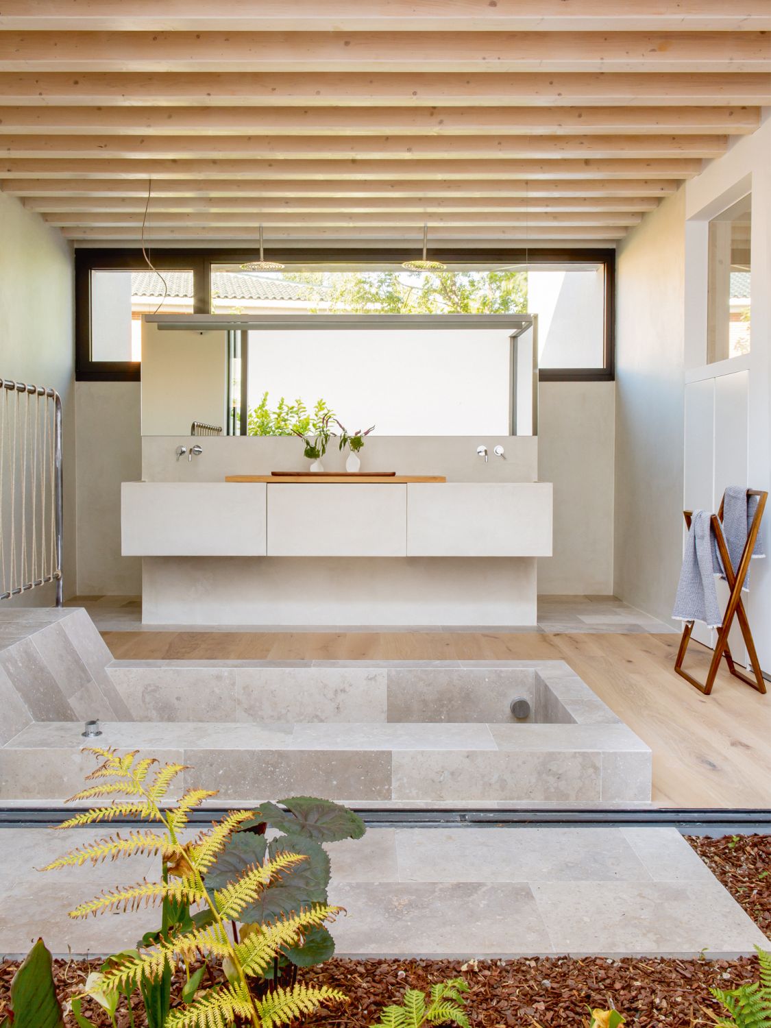 The master bathroom features a recessed bathtub as well as a ceiling and floor clad in cross-laminated timber