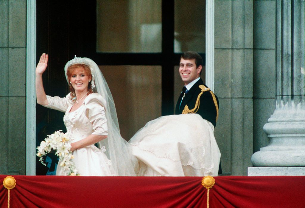 (Original Caption) The Duke of York, Andrew, carries Duchess Sarah Ferguson's train as she waves from the balcony on their wedding day.