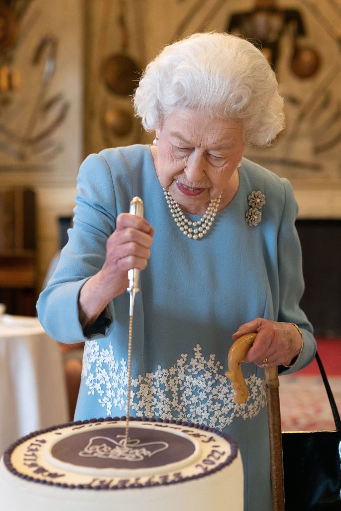 KING'S LYNN, ENGLAND - FEBRUARY 05: Queen Elizabeth II cuts a cake to celebrate the start of the Platinum Jubilee during a reception in the Ballroom of Sandringham House on February 5, 2022 in King's Lynn, England. The Queen came to the throne 70 years ago this Sunday when, on February 6 1952, the ailing King George VI , who had lung cancer, died at Sandringham in the early hours. (Photo Joe Giddens - by WPA Pool/Getty Images)