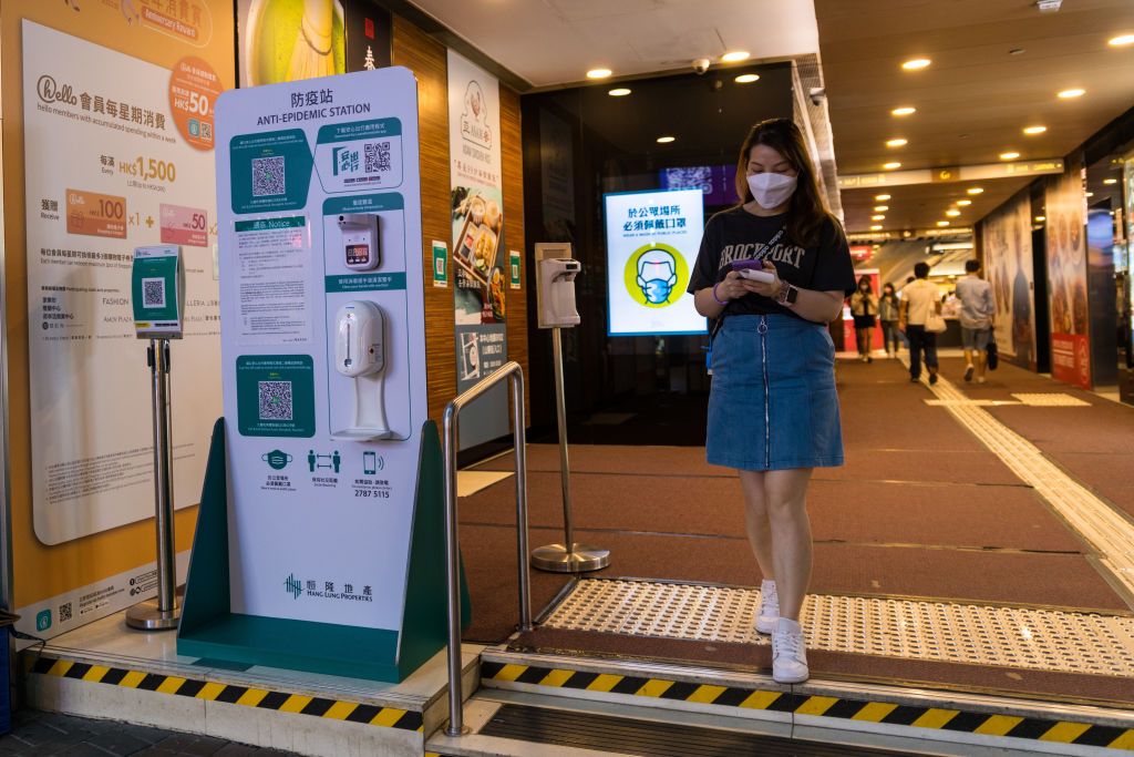 , A lady exits a mall where an "anti-epidemic station" invites people to scan a QR code for the LeaveHomeSafe app, take their temperature and disinfect their hands, on April 16, 2022. (Photo by Marc Fernandes/NurPhoto via Getty Images)